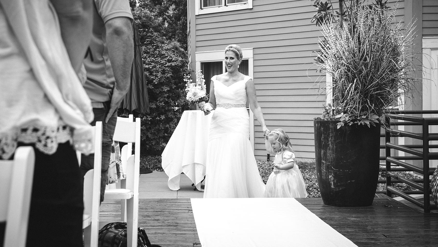 bride with child walking down aisle at outdoor hotel wedding venue