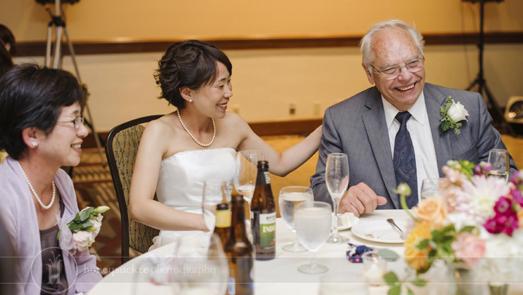 bride sitting and smiling with parents at wedding reception
