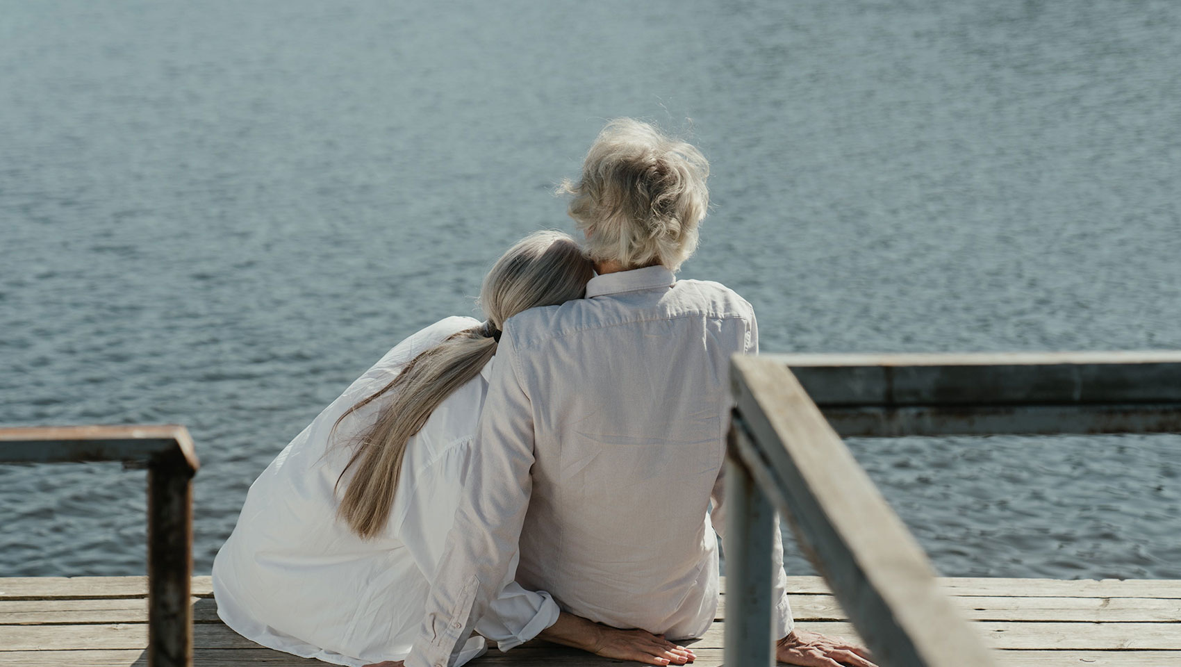 two seniors sitting on a dock looking out at the water