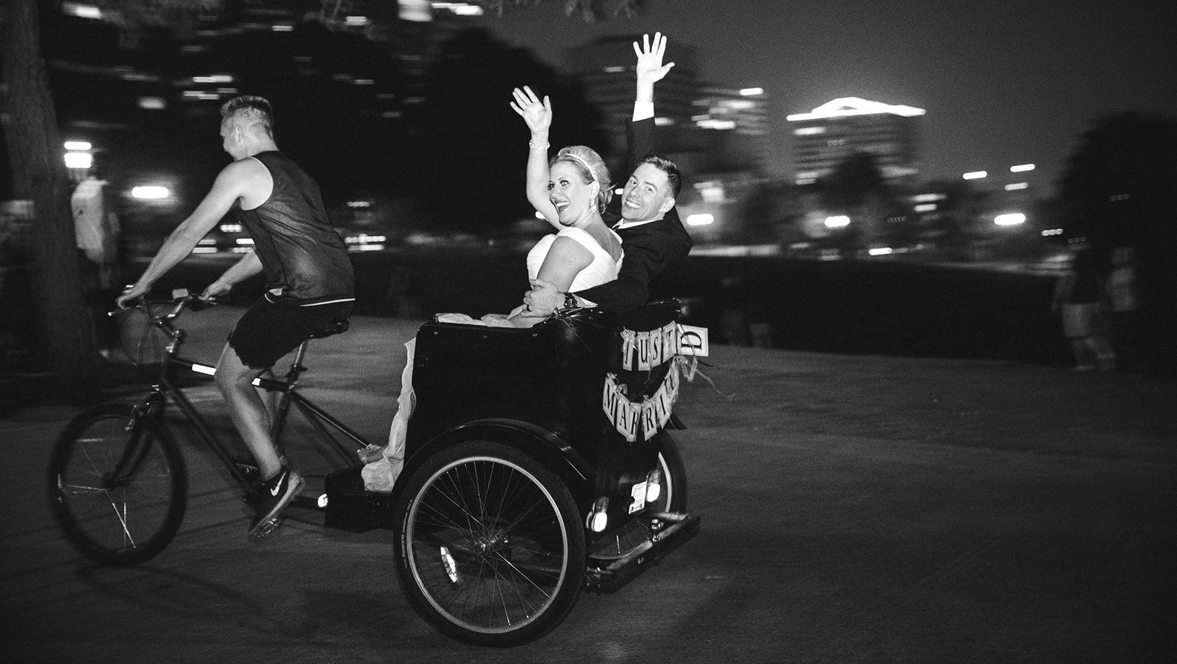 bride and groom riding in pedicab waving