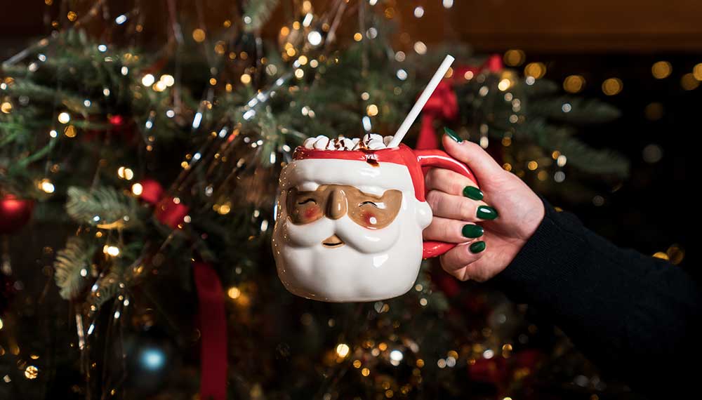 A Santa Claus mug in front of a Christmas tree
